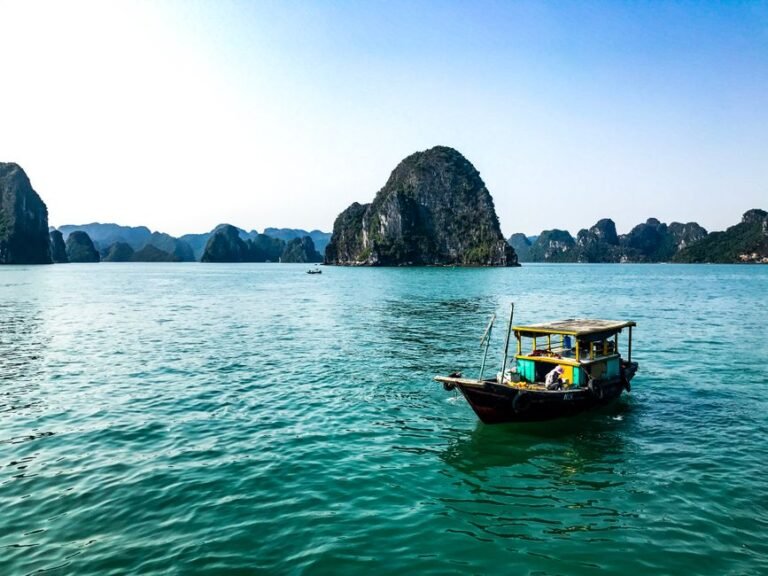 Cảnh vịnh Hạ Long hùng vĩ với những núi đá vôi và thuyền buồm truyền thống, tượng trưng cho tour du lịch trọn gói trong nước của Nam Việt Travel