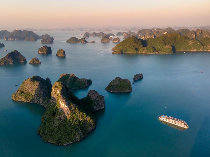 Vịnh Hạ Long huyền ảo với bình minh buông xuống trên những hòn đảo đá vôi và thuyền buồm truyền thống.