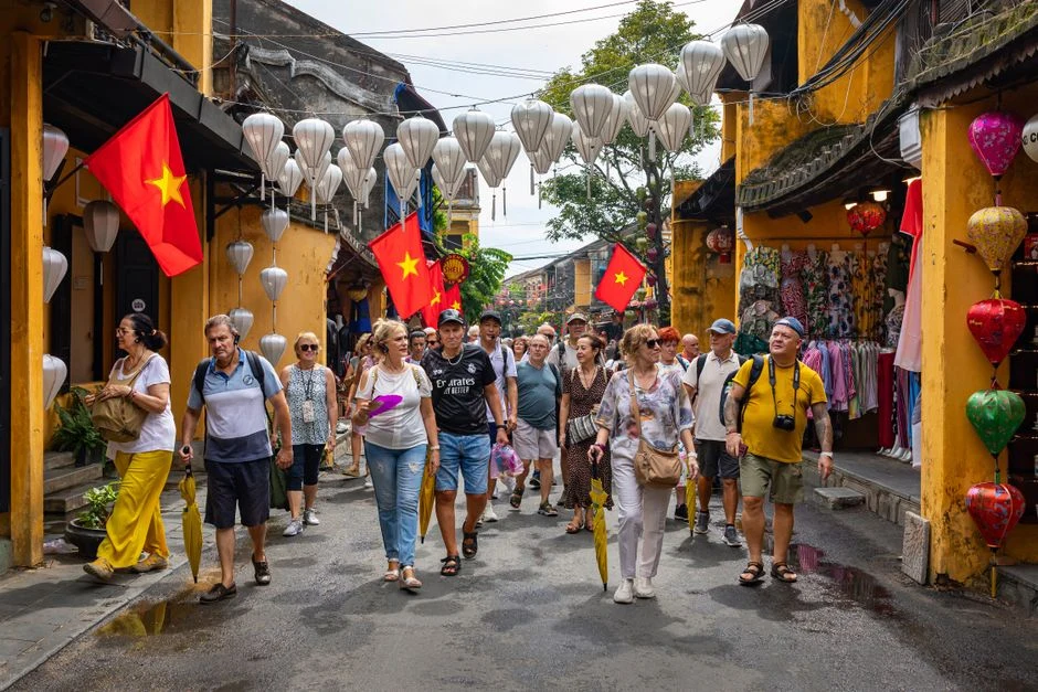 Nhóm du khách vui vẻ tương tác với hướng dẫn viên Nam Viet Travel tại chợ địa phương, thể hiện dịch vụ cá nhân hóa